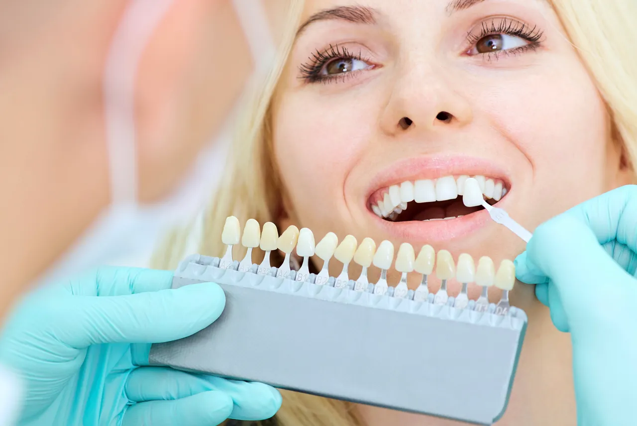 A clinician matching veneer shades for a female patient.