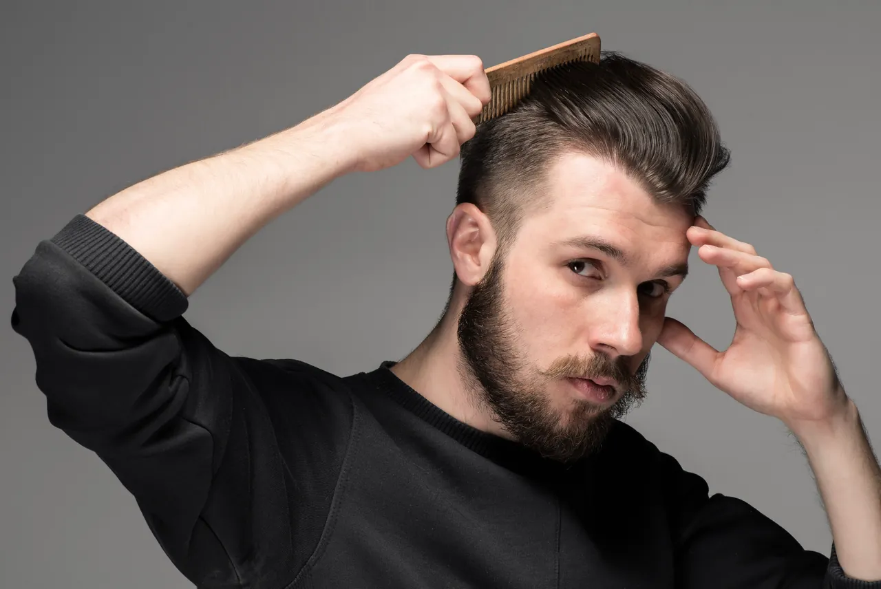 A man grooming his hair and beard with a comb.